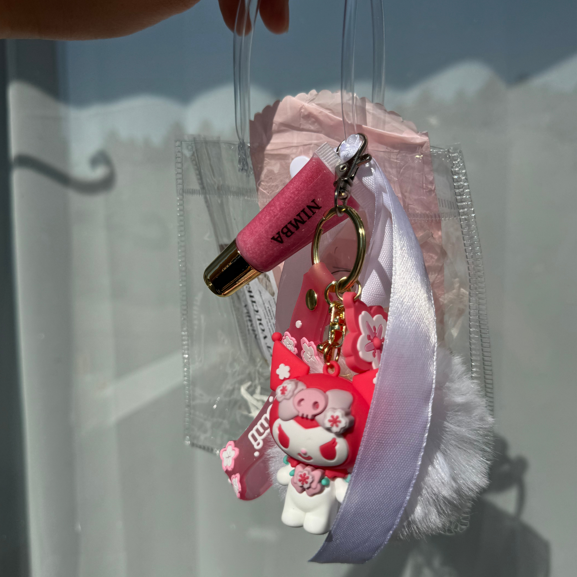 NIMBA pink lip gloss keychain attached to a cherry blossom-inspired charm. Hydrating, vegan, and handmade for natural lip care lovers