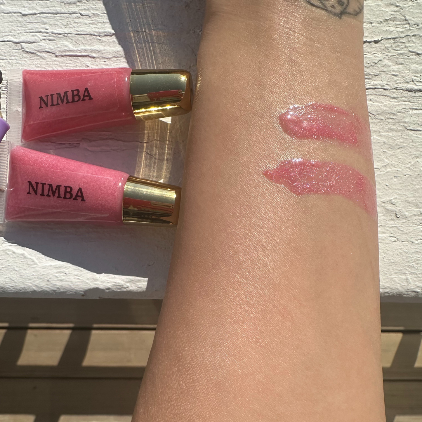 Swatches of NIMBA pink hydrating lip gloss on the skin, showcasing the natural, vegan formula’s glossy finish. Perfect for everyday lip care